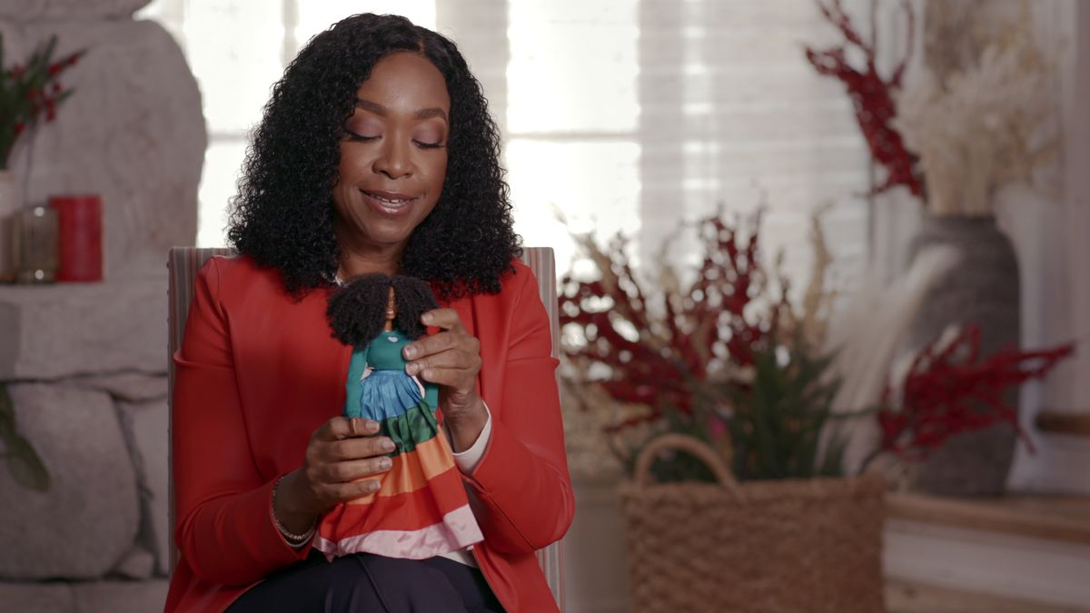 A woman holding a barbie in Black Barbie.