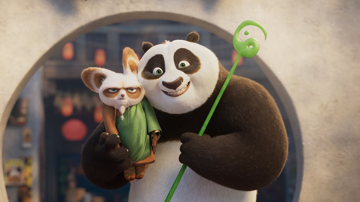 An anthropomorphic panda holding a green scepter and a red panda in his arms while smiling.