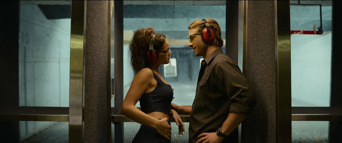 Adria Arjona and Glen Powell stare romantically into each other’s eyes at a firing range in Hit Man