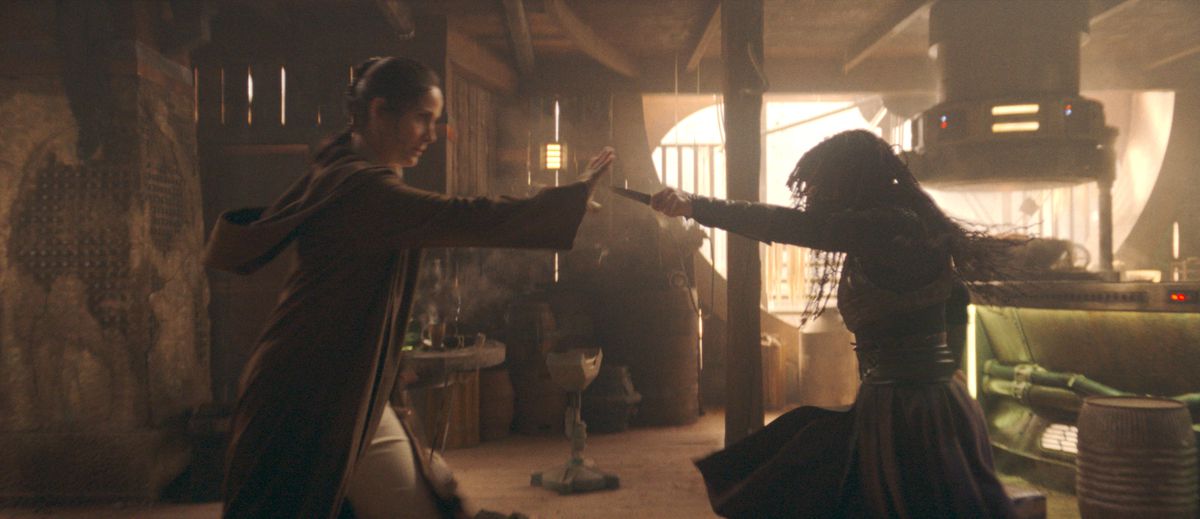 (L-R): Jedi Master&nbsp;Indara&nbsp;(Carrie-Anne Moss) and Mae&nbsp;(Amandla Stenberg) square off in The Acolyte. Indara is holding Mae’s outstretched dagger using the Force.