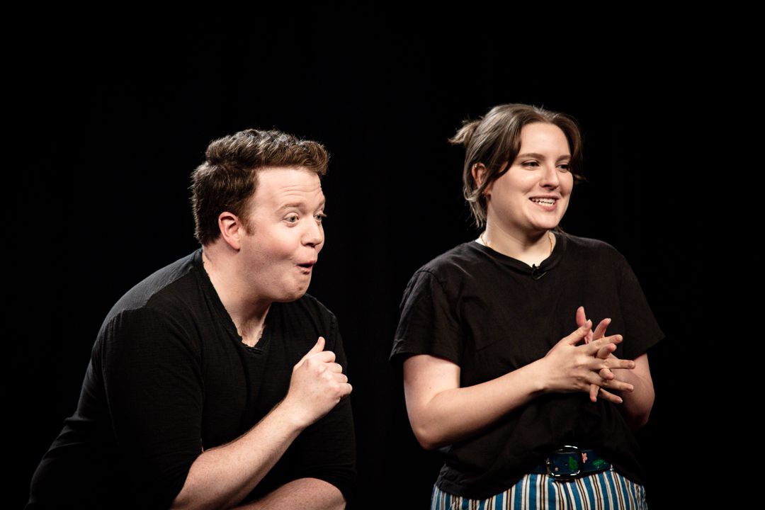 Brennan Lee Mulligan and Izzy Roland react with glee on stage in Bigger