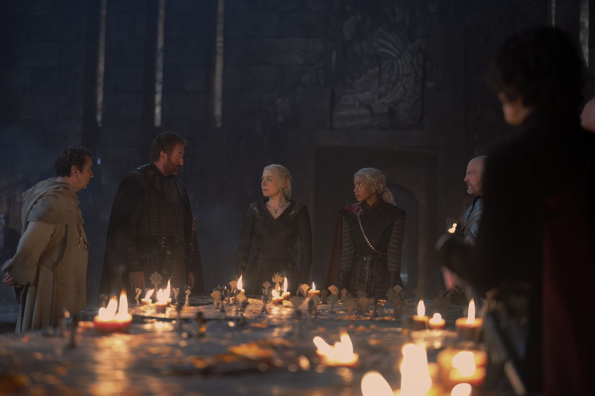 Rhaenyra stands behind the candlelit war table with her small council in House of the Dragon season 2