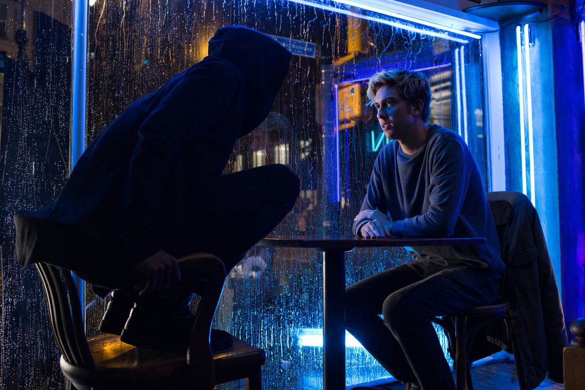 In a still from Netflix’s live-action Death Note movie, Lakeith Stanfield stands on a chair as L while sitting across from Nat Wolff as Light