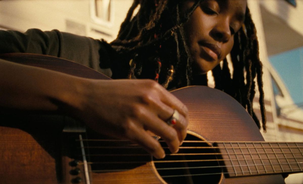 A close-up shot of a woman playing guitar in Dandelion.