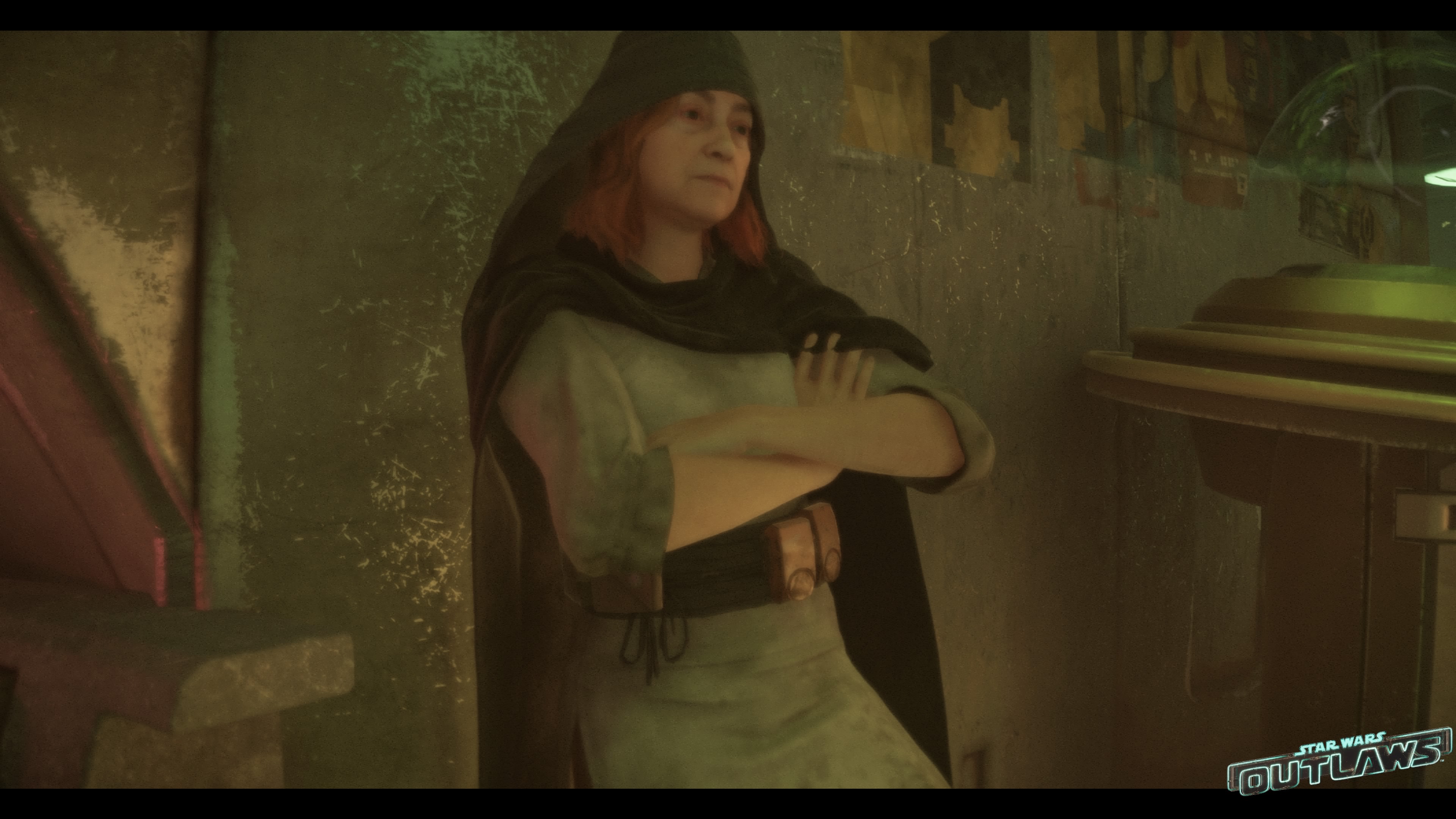 A middle-aged woman with a black shawl over her red hair leans against a wall, her arms crossed