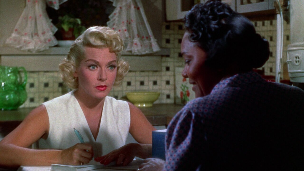 Lora (Lana Turner) and Annie (Juanita Moore) sitting across from each other at a dinner table in Imitation of life (1959).