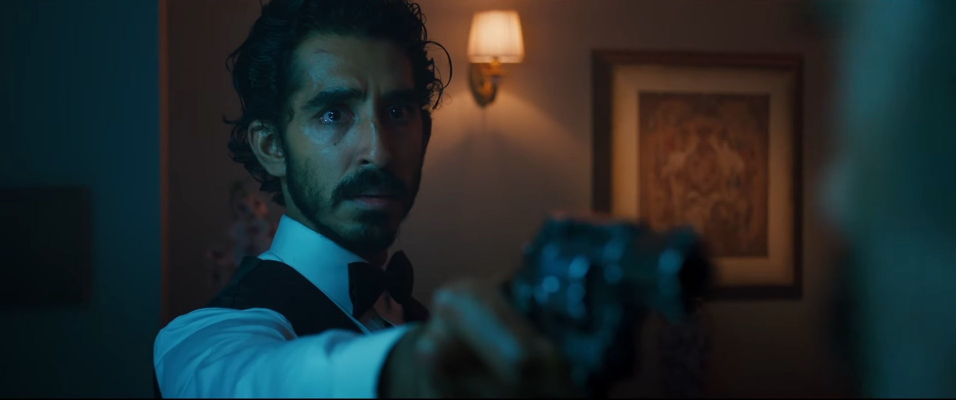 Dev Patel holds a gun and looks sad in fancy dress in Monkey Man