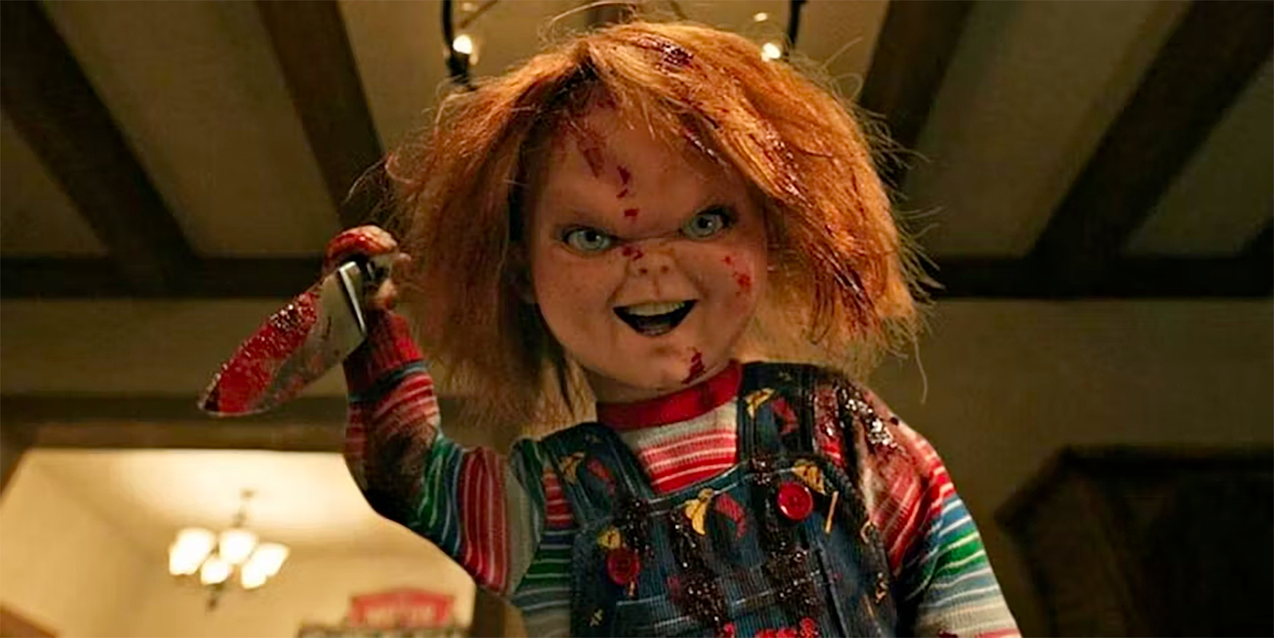 Chucky holds a bloody knife aloft ready to stab someone in a still from season 3 of Chucky