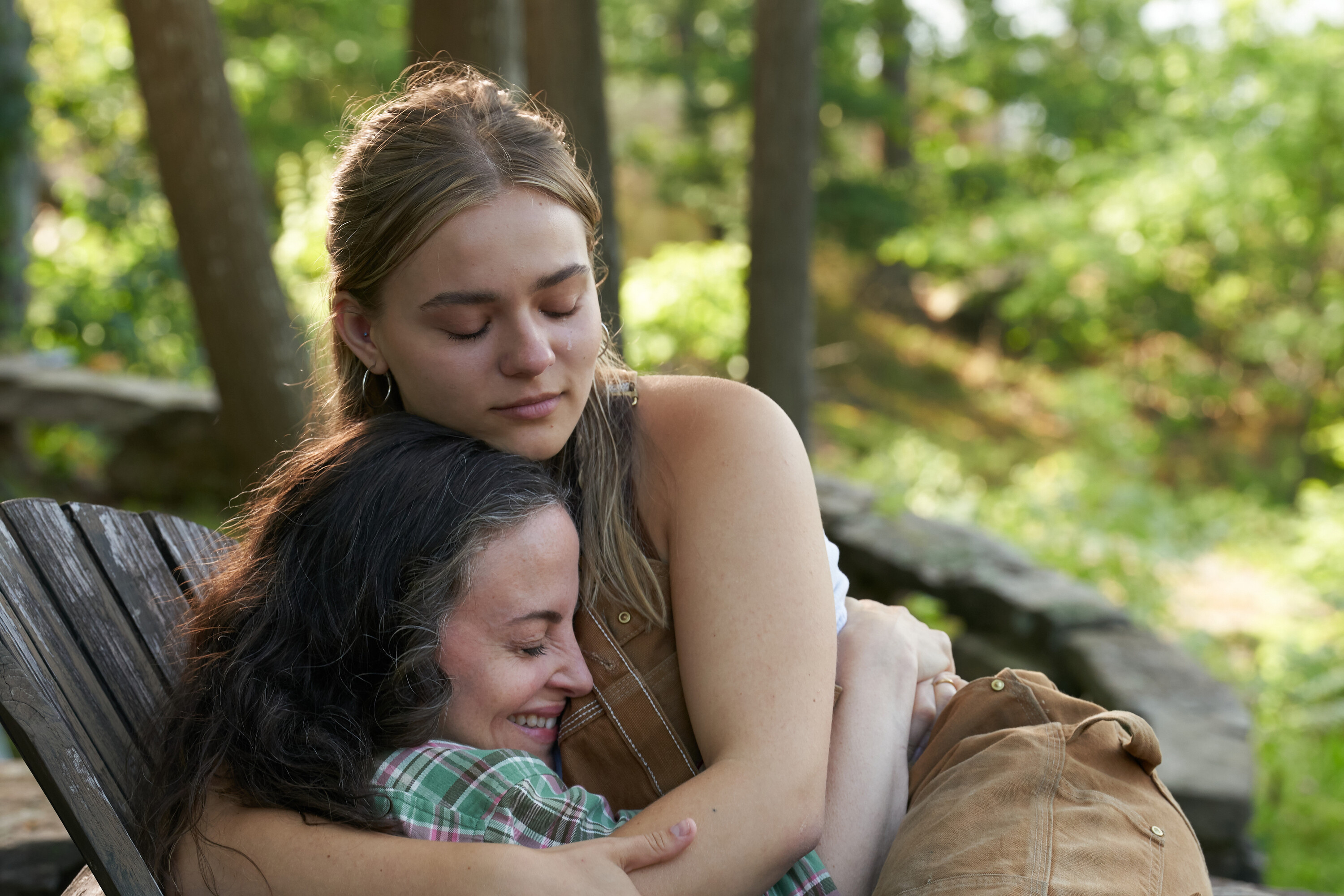 Elliott, a young blonde woman played by Maisy Stella, hugs her mother, played by Maria Dizzia, on an outdoor chair in My Old Ass