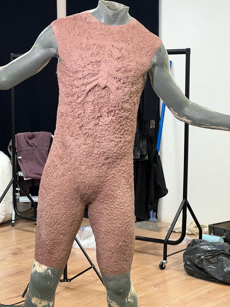 A behind the scenes shot of a burned one prosthetic before it’s painted, looking like a unisuit with no sleeves and cut off at the knees