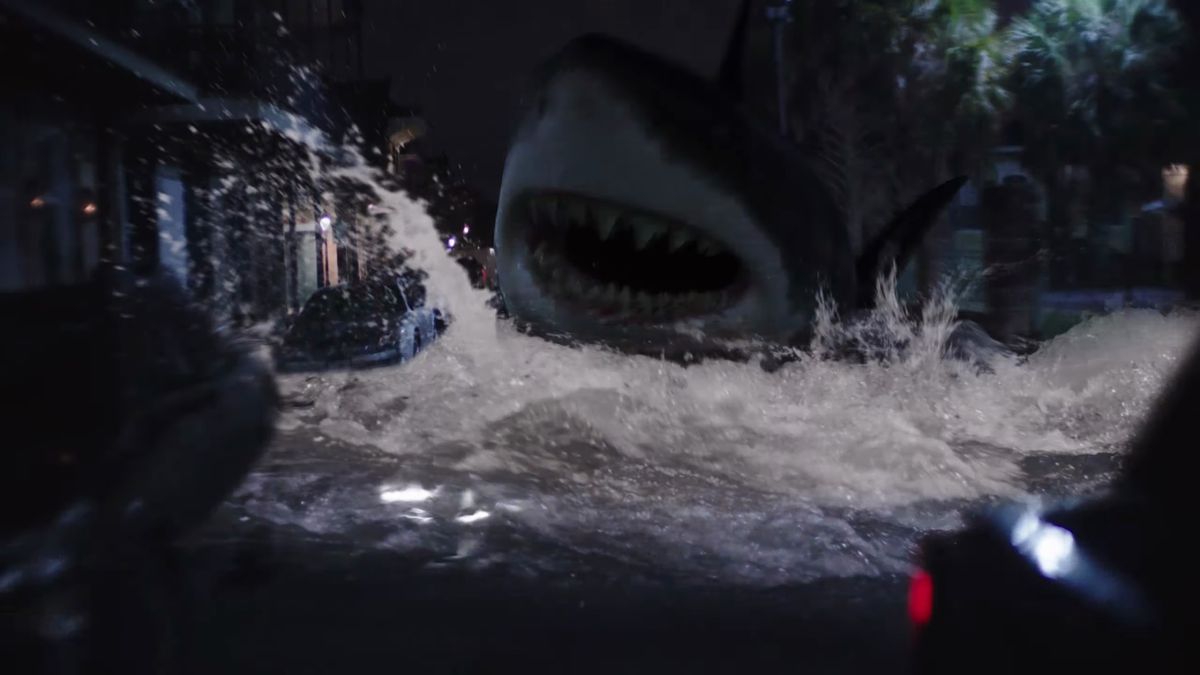 An underlit night shot from Tommy Wiseau’s Big Shark shows a building-sized great white lunging along a New Orleans street on top of the water