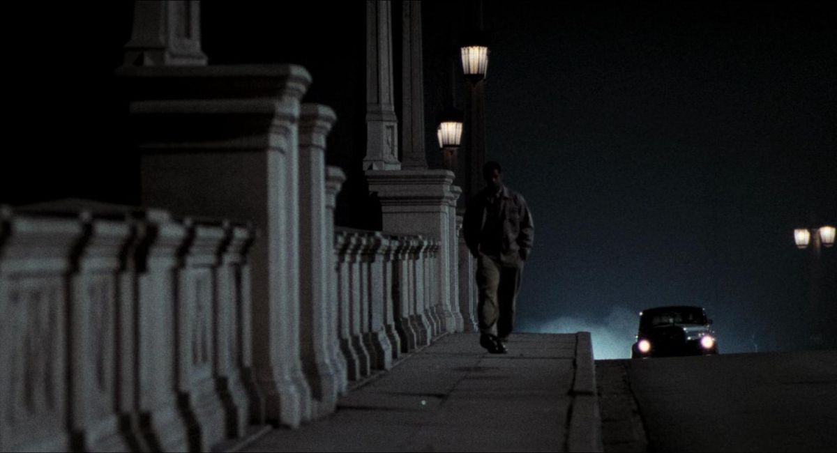 Denzel Washington walks along a bridge at night as a car approaches in Devil in a Blue Dress