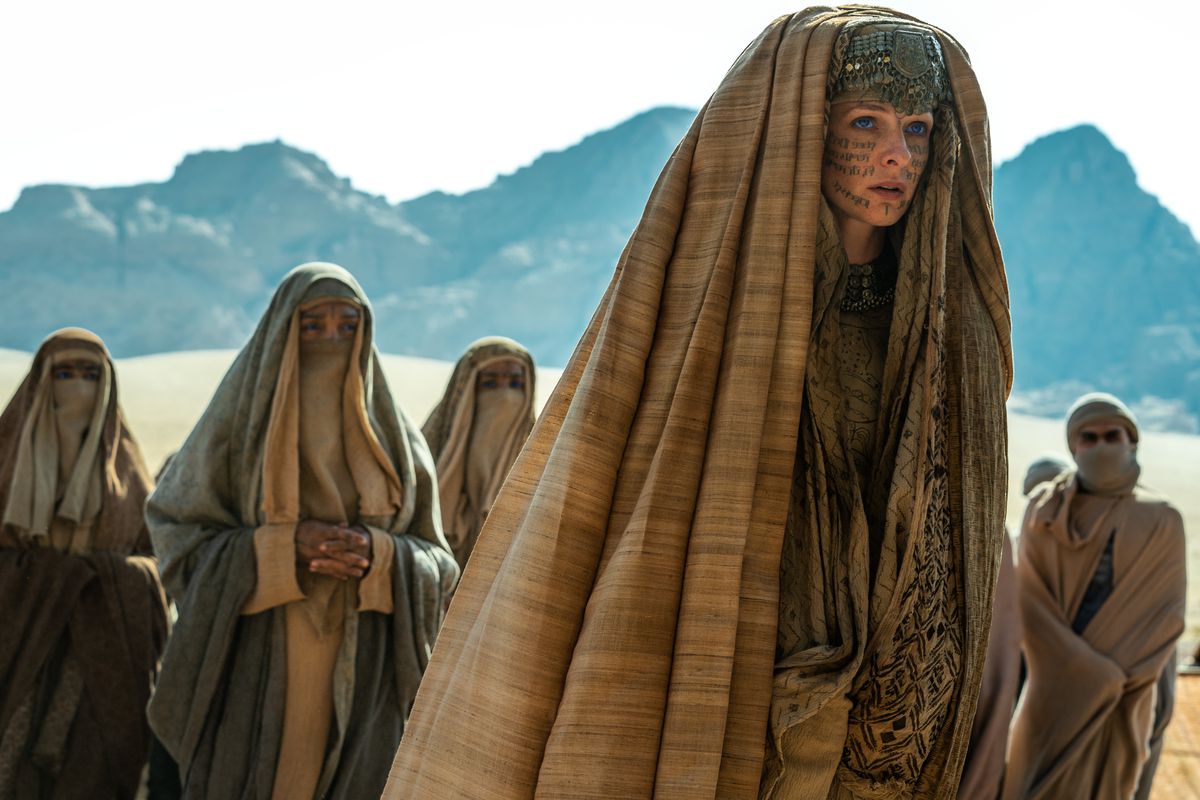 Lady Jessica (Rebecca Ferguson), cowled and with symbols written across her face in ink, stands in the desert, surrounded by similarly robed figures in Denis Villeneuve’s Dune: Part Two