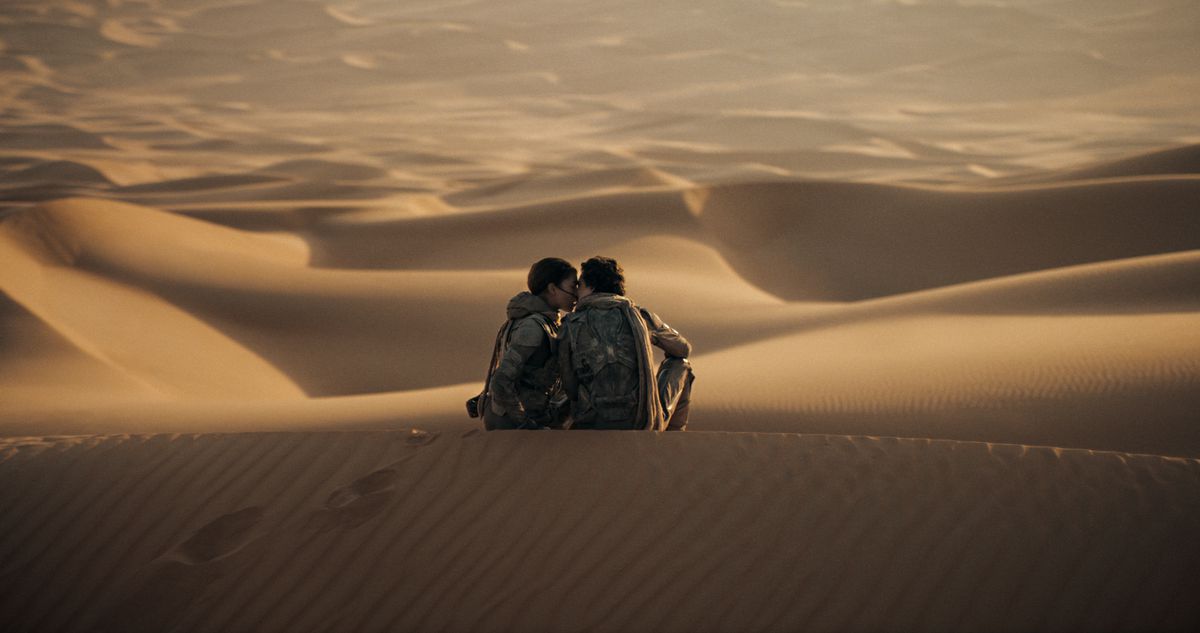 Timothée Chalamet’s Paul and Zendaya’s Chani kiss on the top of a sand dune in Dune: Part Two. 
