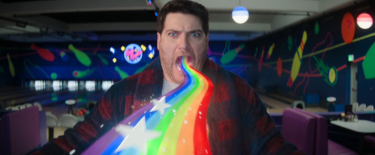 Adam Pally barfing a rainbow in stars while in a bowling alley in the Knuckles show