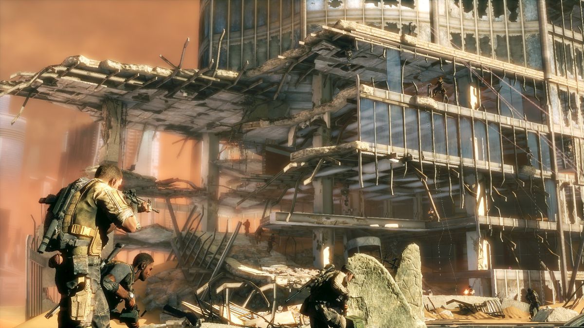 Soldiers approach a bombed-out building in the desert in a screenshot from Spec Ops: The Line