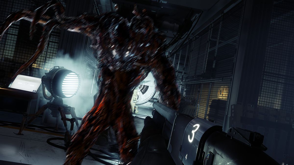 A Typhon-infested crew member of the Talos I threatens the protagonist. The creature is a space suit full of black, inky material that sprawls out into tentacles. The Typhon is standing in an industrial hallway.