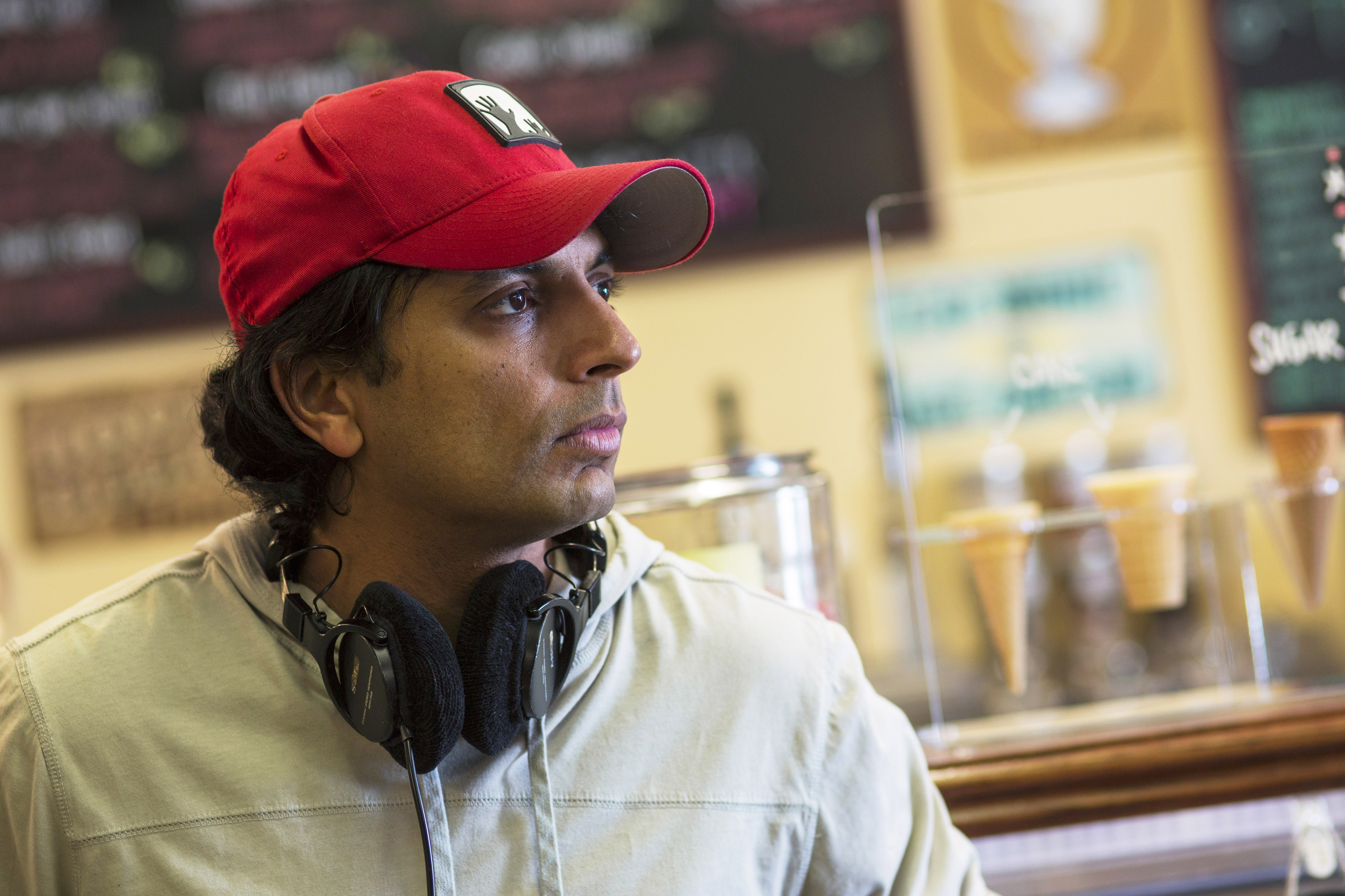 M. Night Shyamalan on the set of The Visit wearing headphones on his neck 