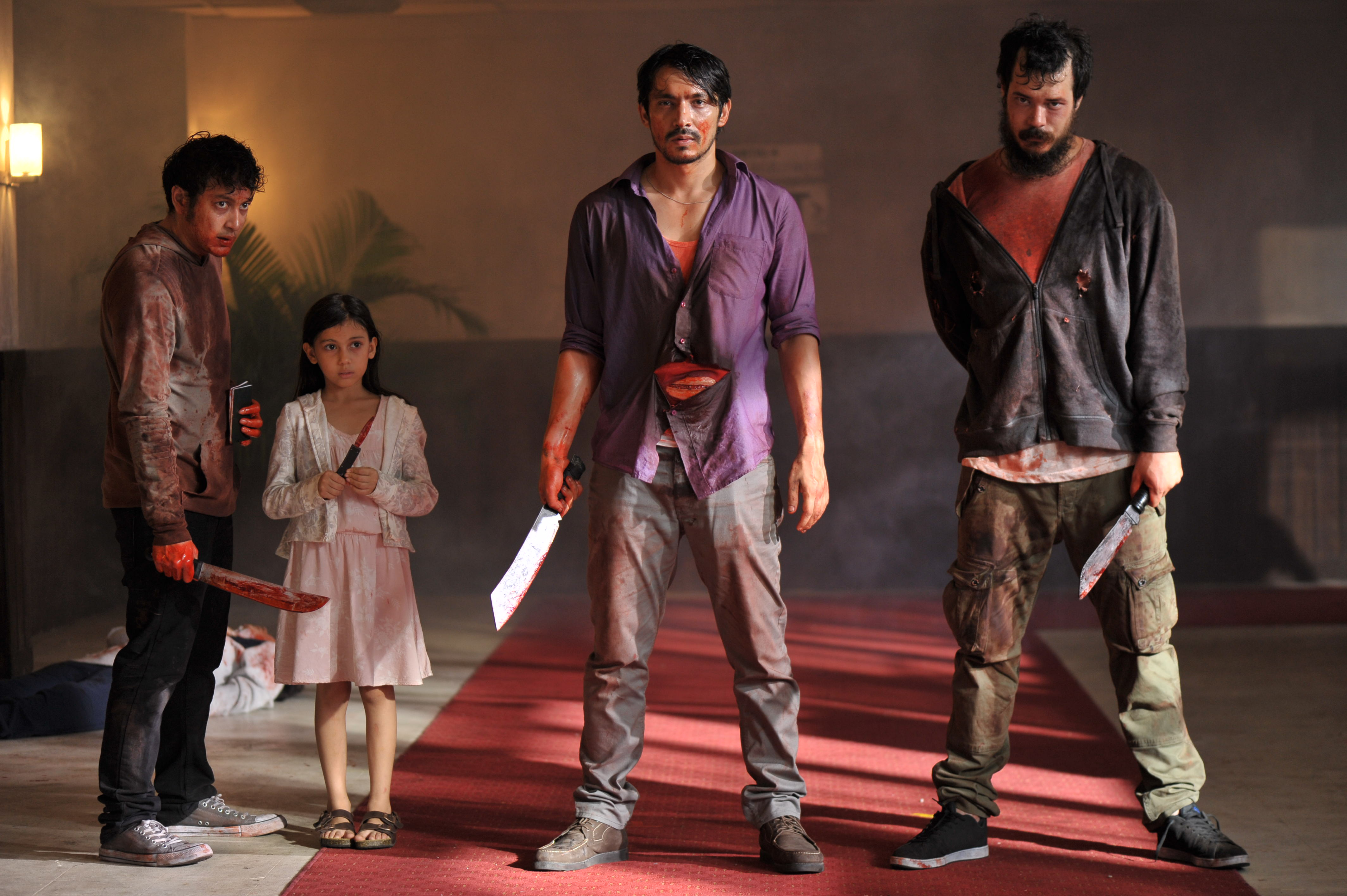 In The Night Comes For Us, three bloody men (and one small girl) hold bloody knives and look towards the camera