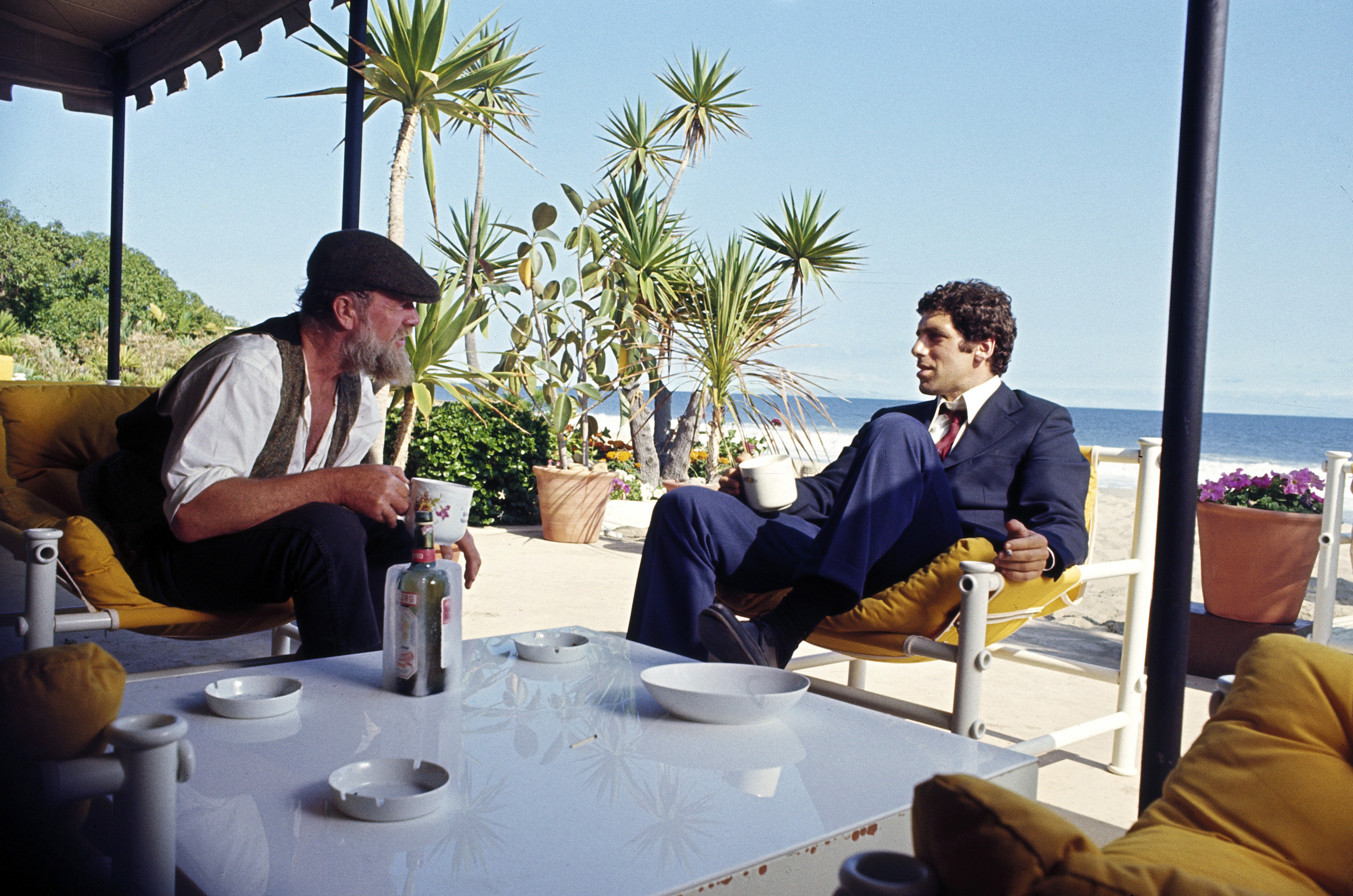 Elliott Gould and Sterling Hayden drink out of mugs while sitting by the beach in The Long Goodbye