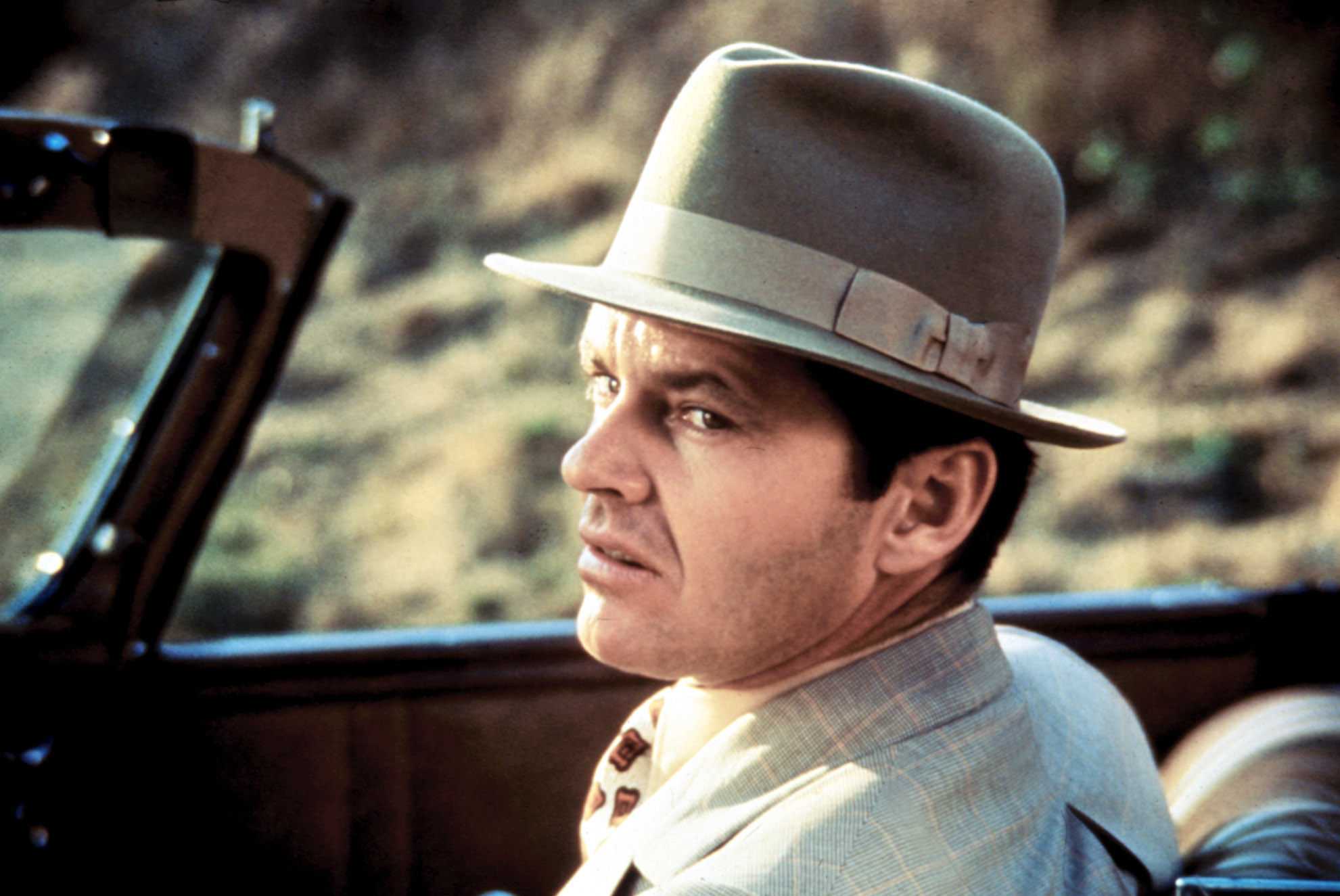 Jack Nicholson, wearing a fedora, in a car in Chinatown