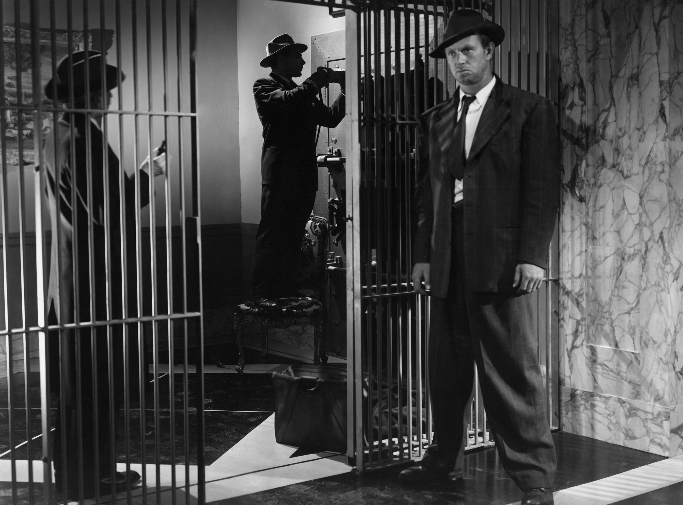 In the Asphalt Jungle, the heist is afoot — Sterling Hayden waits while Sam Jaffe and Anthony Caruso attempt to break into a safe