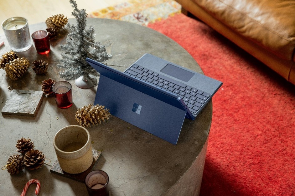 Surface device on a coffee table decorated with pinecones, candles and a miniature Christmas tree