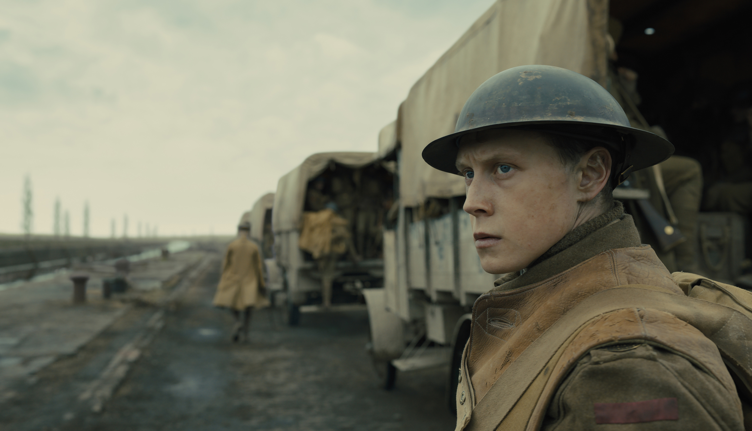 Lance Cpl. Will Schofield (George MacKay) looks ahead as army trucks drive by in 1917