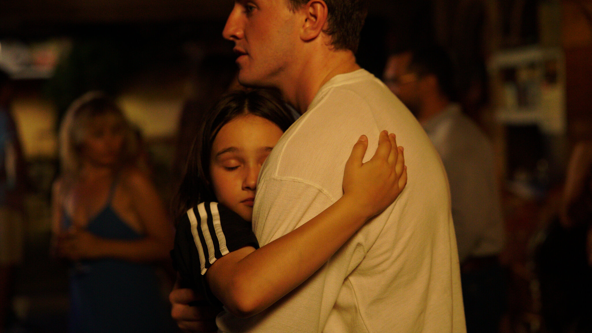 A young girl holding a man on a dance floor in Aftersun.