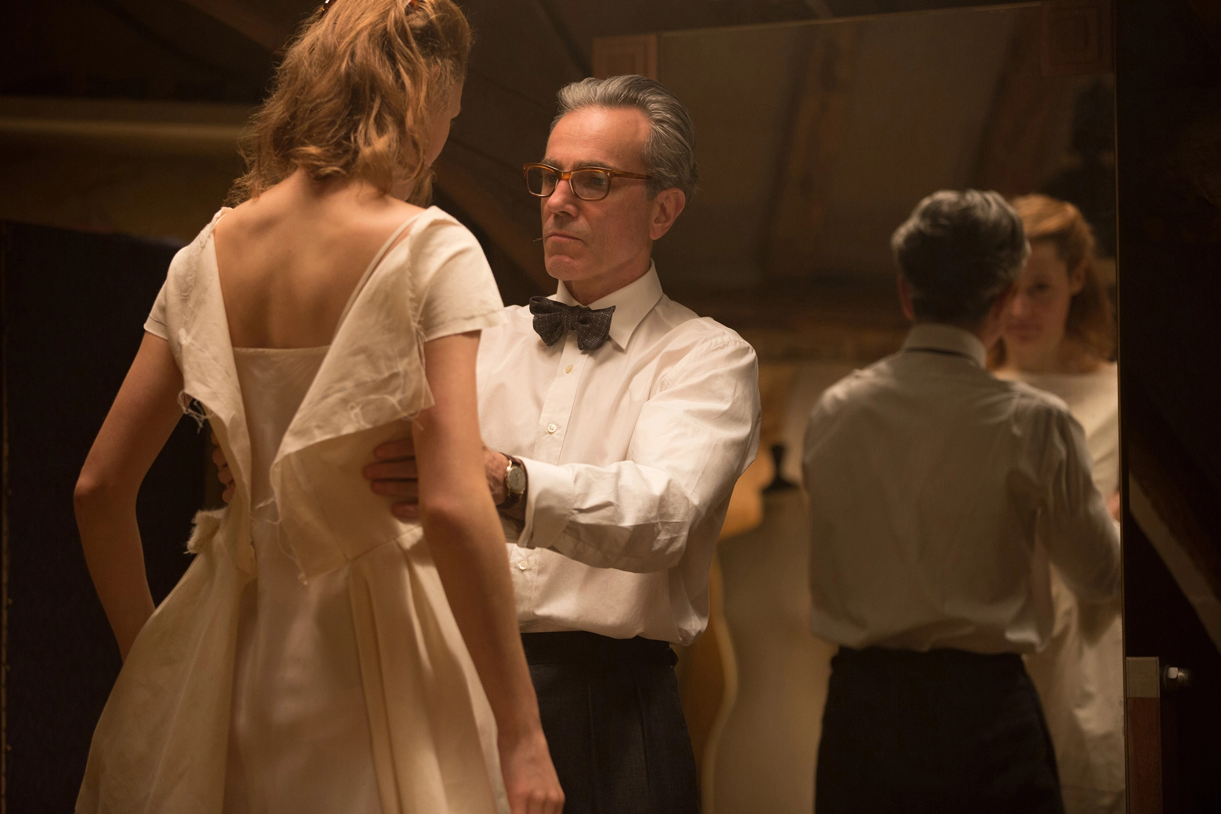 Reyolds Woodcock (Daniel Day-Lewis) sizing up a dress on Alma (Vicky Krieps) in Phantom Thread.