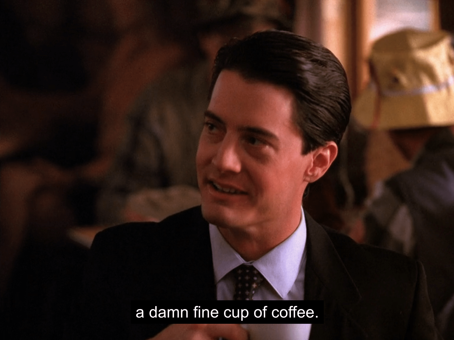 Dale Cooper looking at someone smiling and saying “a damn fine cup of coffee” in a still from Twin Peaks season 1