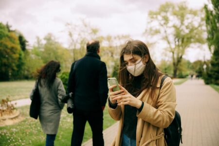 Group of people walking outdoors while looking at their mobile phones, representing mobile gaming community engagement