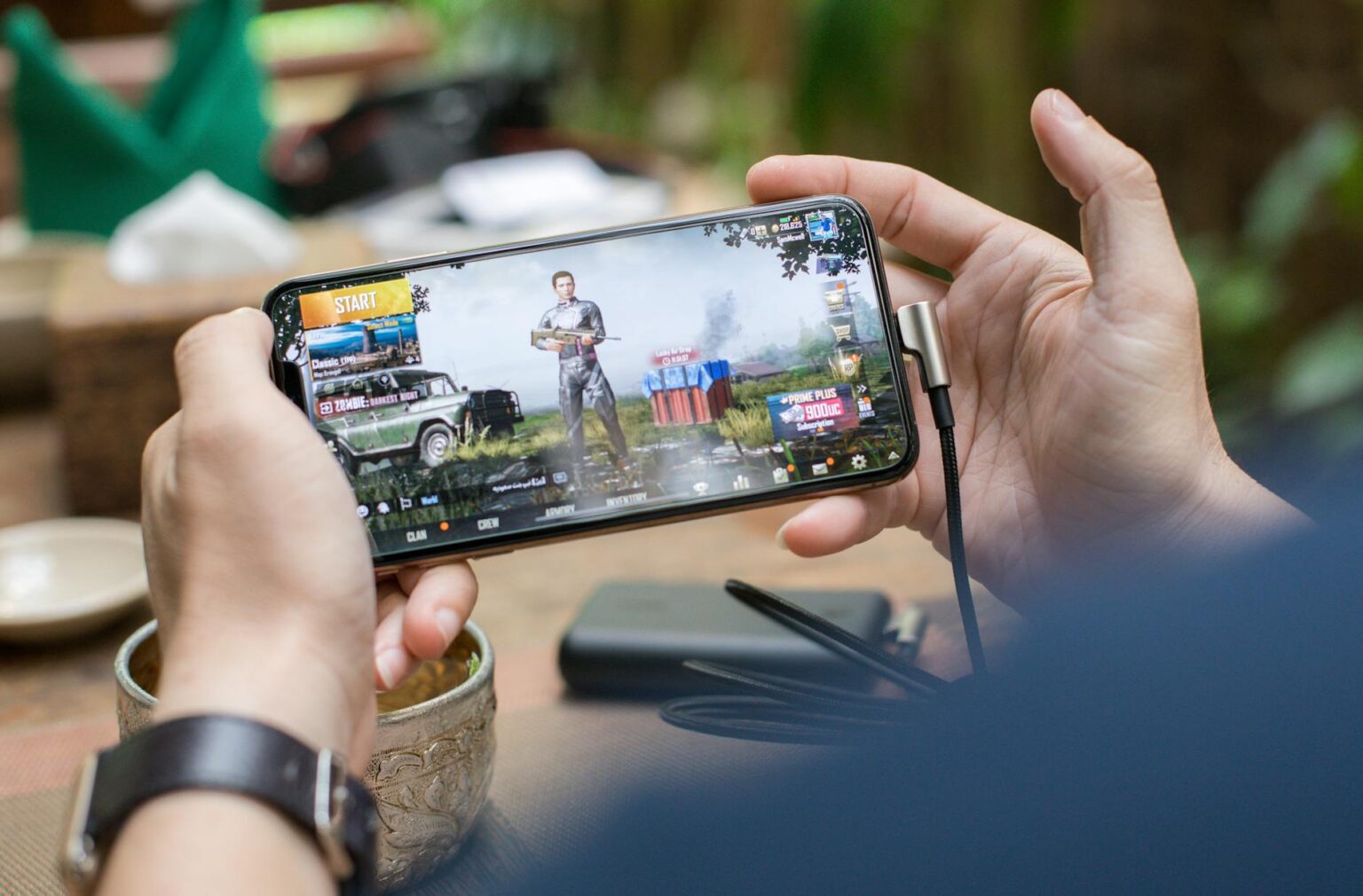 Person playing mobile game on smartphone with colorful interface visible on screen