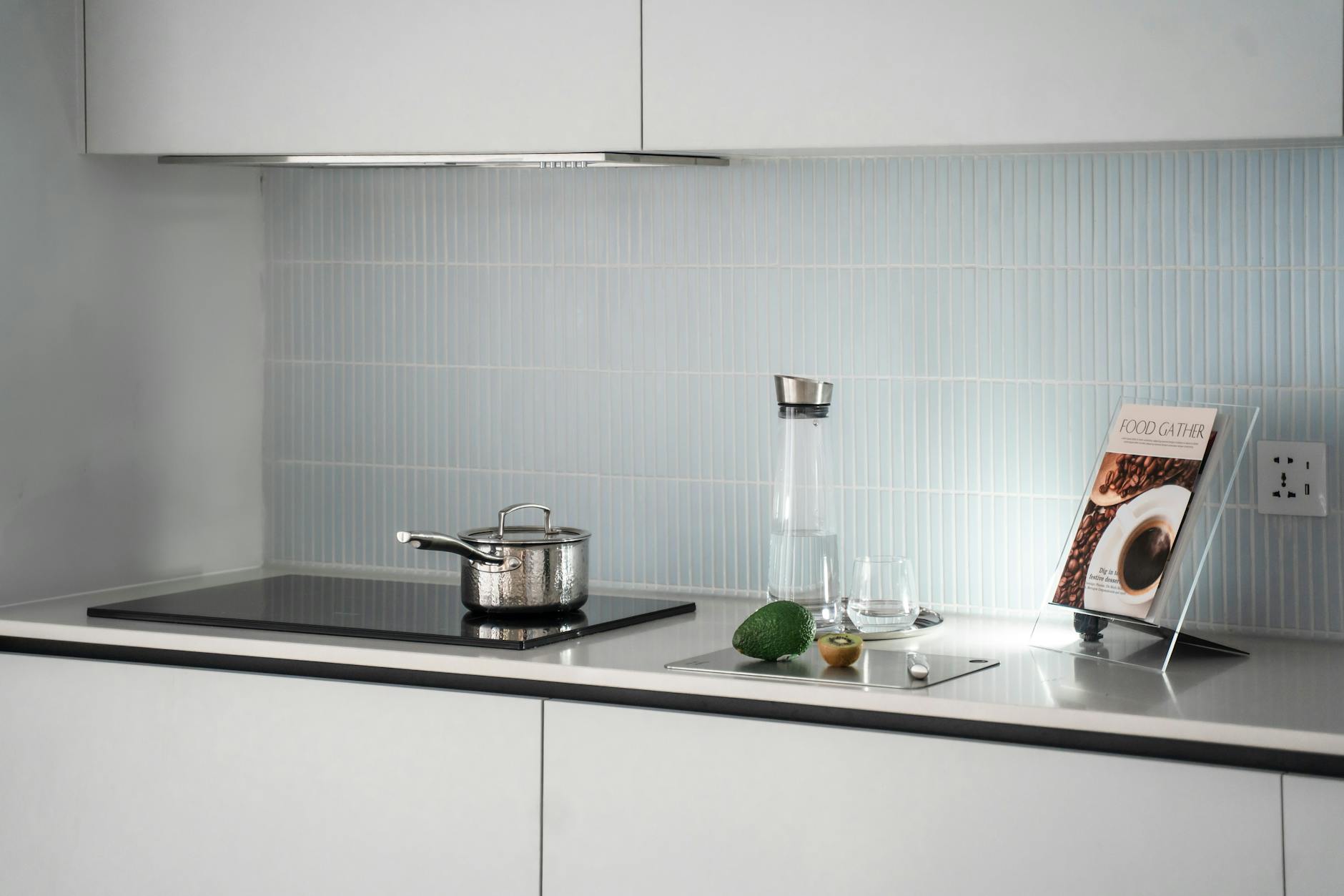 Open cookbook on kitchen counter with cooking ingredients and utensils around it