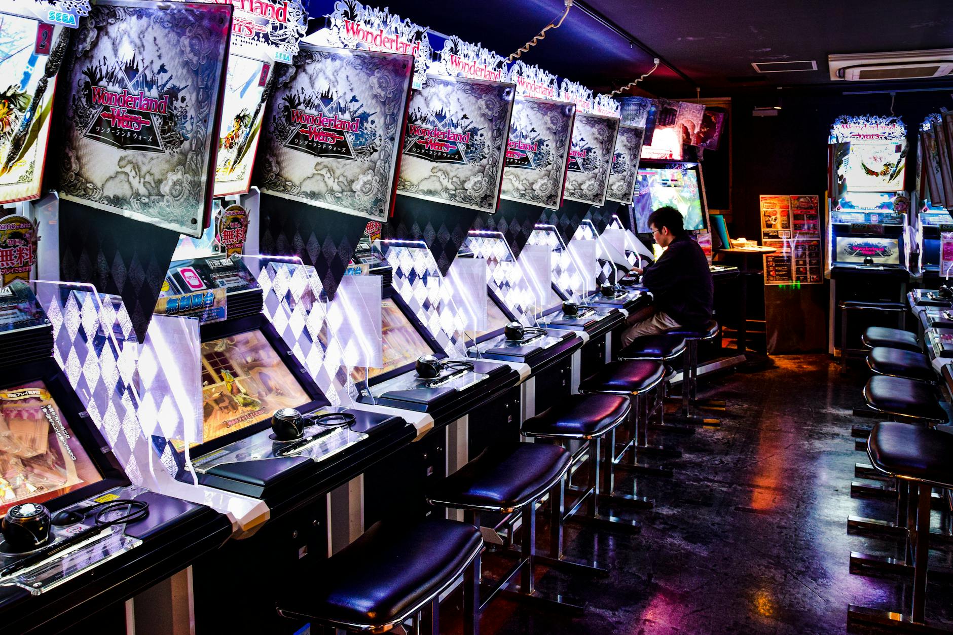Busy Japanese gaming cafe with multiple gaming stations and neon lighting