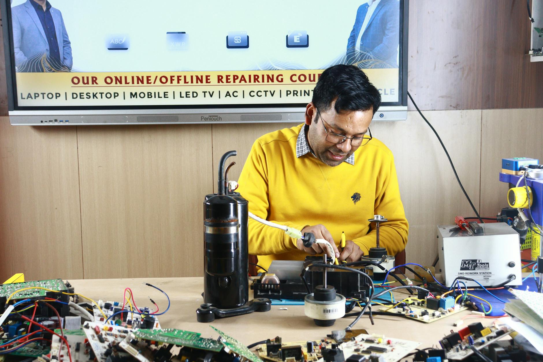 Technician working on electronic device repair with precision tools