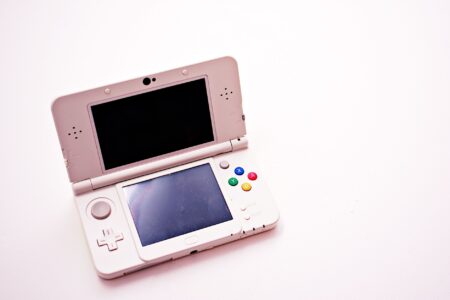 A handheld gaming device held in hands against a dark background