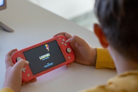 Switch 2’s GameChat Feature Is Fragmenting Discord’s Handheld Audience Person playing a handheld gaming console on a couch