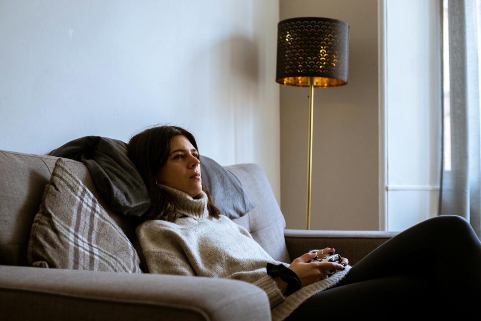 Two people playing a video game together on a couch with a television in the background
