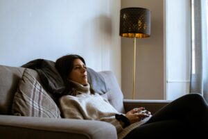 Two people playing a video game together on a couch with a television in the background