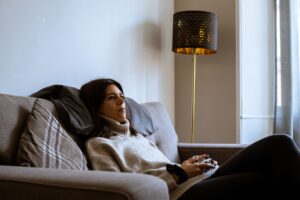 Two people playing a video game together on a couch with controllers in hand