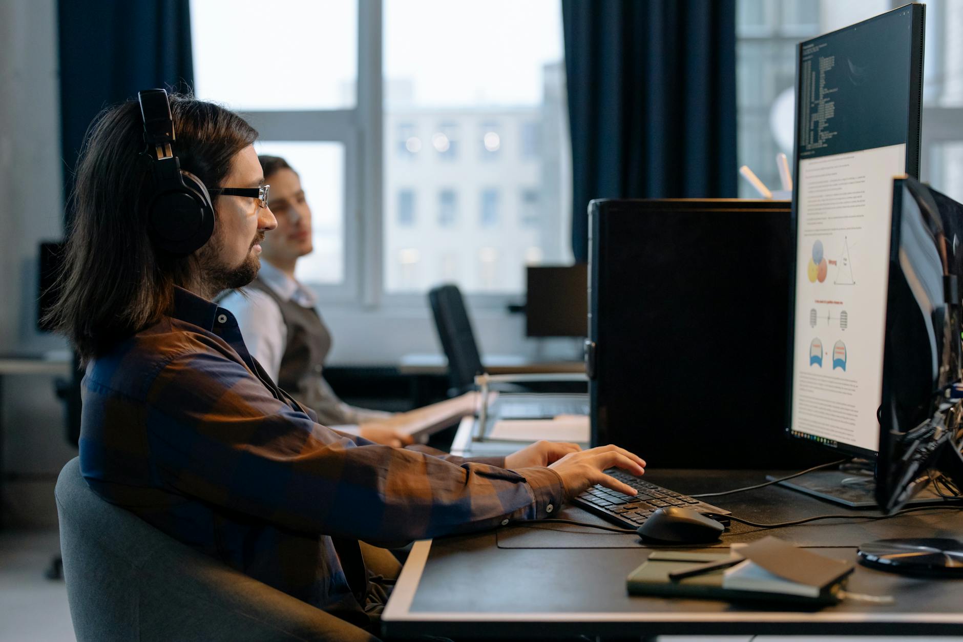 Two developers reviewing technical documentation at a workstation