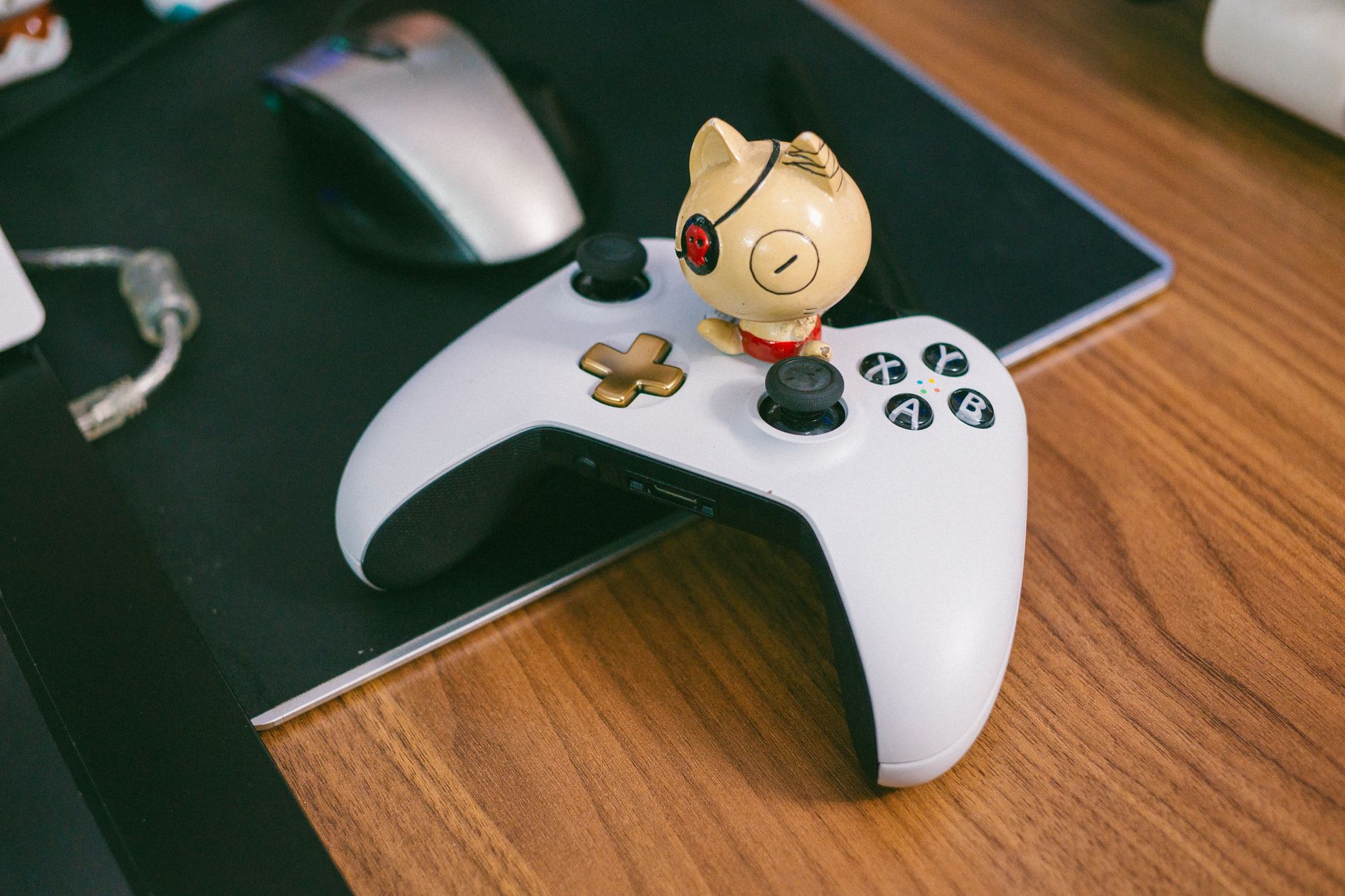 Xbox gaming controller resting on a desk next to a monitor