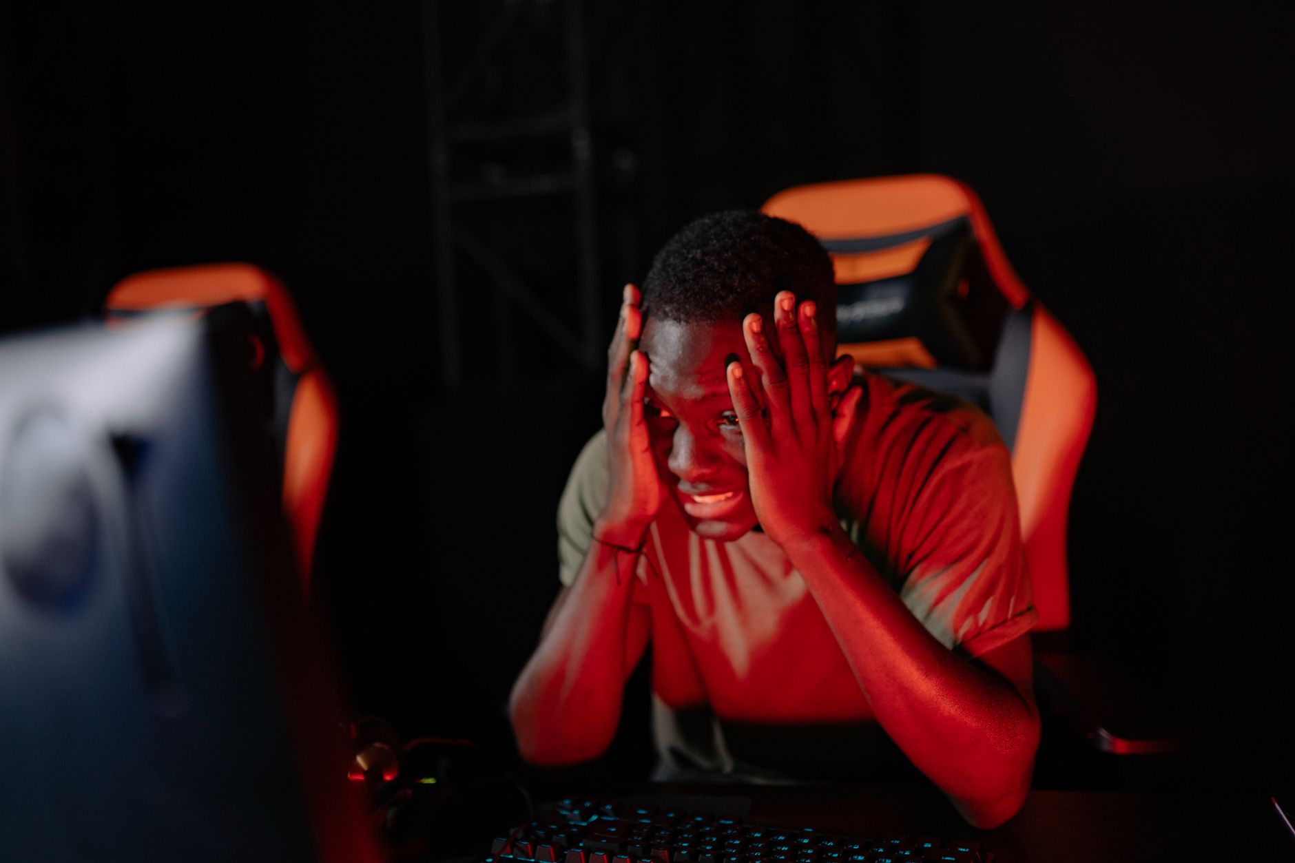 A person sitting at a computer looking frustrated at a gaming screen