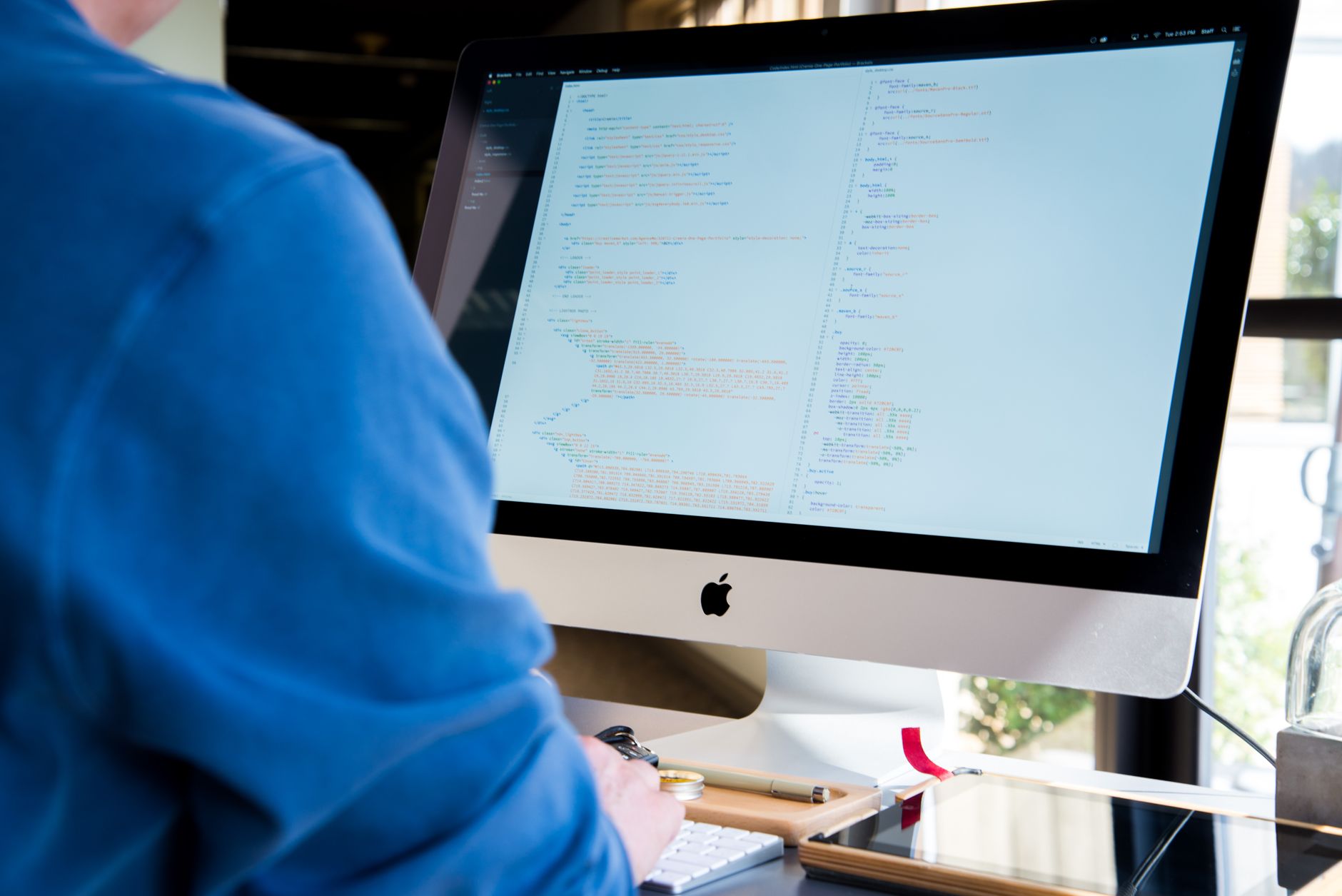 An indie game developer working at a desk with multiple monitors showing code