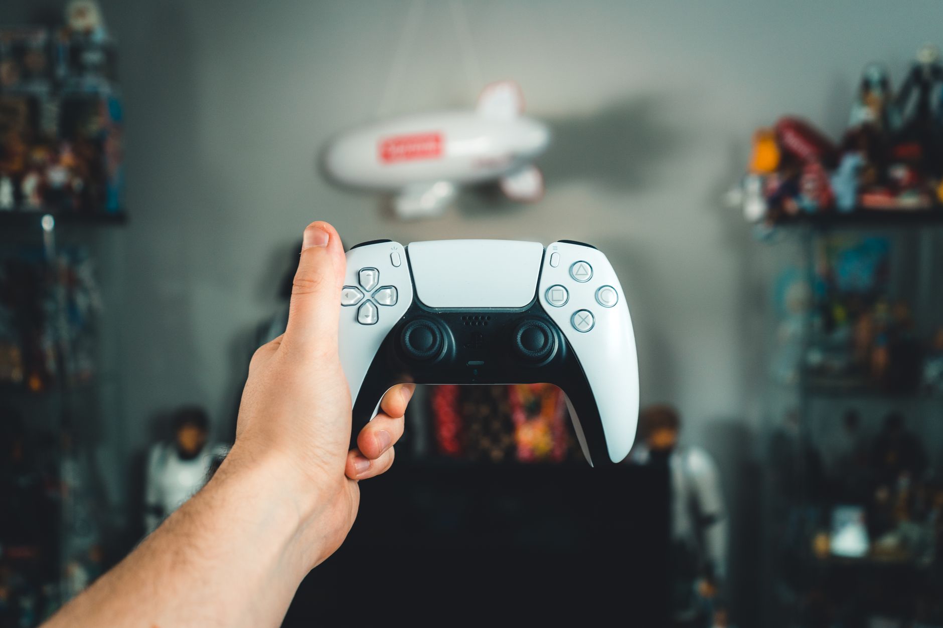 A PlayStation 5 console displayed in a home entertainment setup with a controller in the foreground