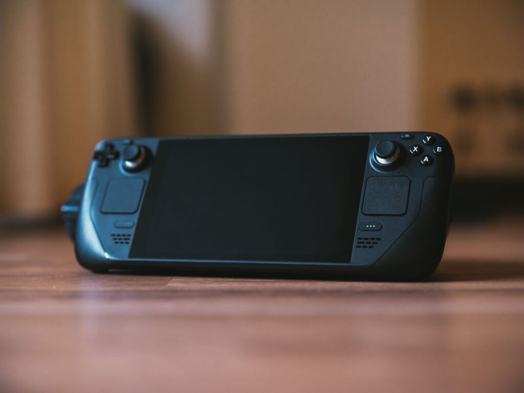 Person playing a handheld gaming console with a colorful game on screen