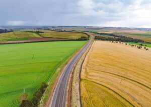 Mario Kart World’s Free Roam Design Is Losing Completionist Players Aerial view of an open road stretching across a colorful landscape, representing free roam exploration