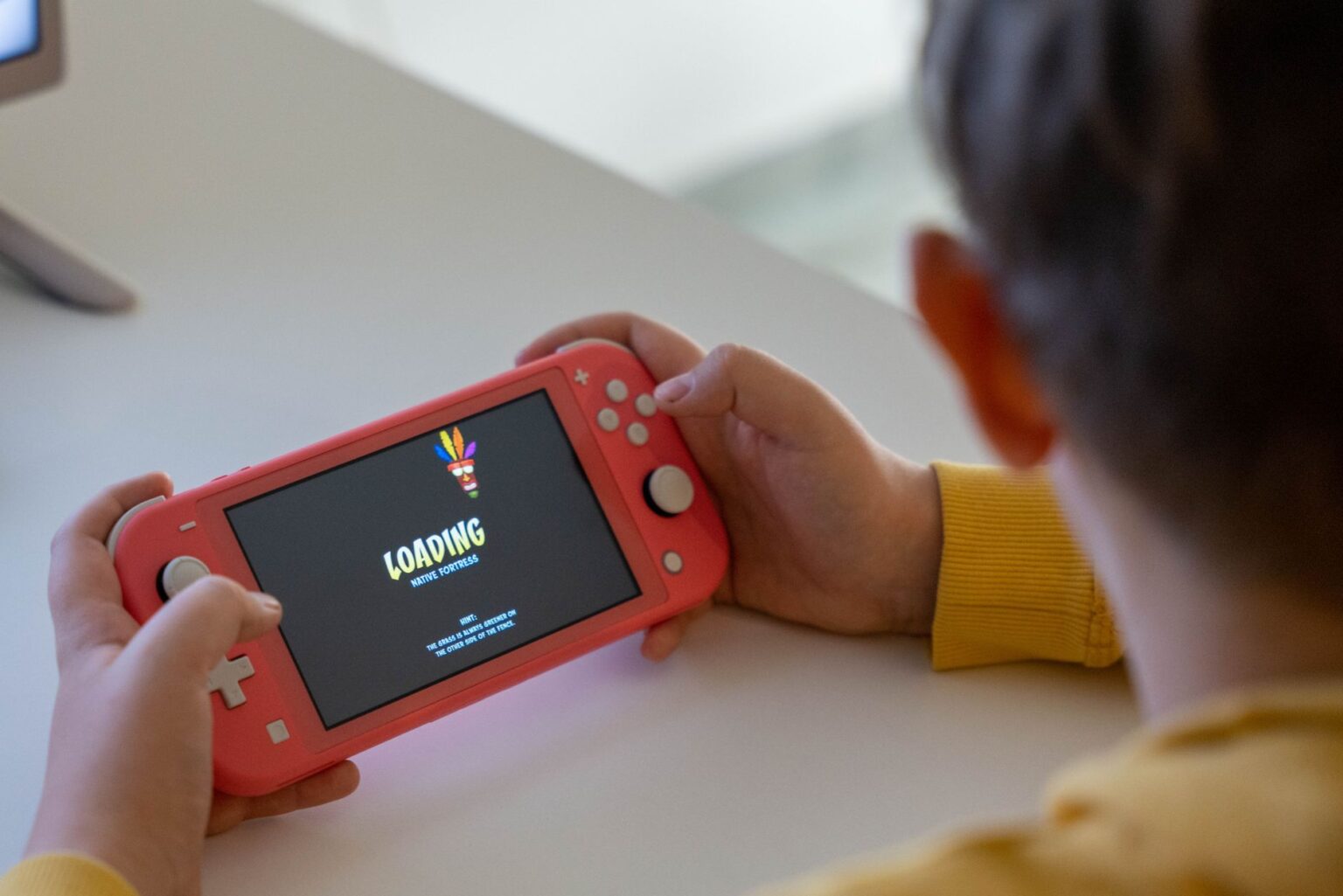 Person holding a handheld gaming console while playing a game