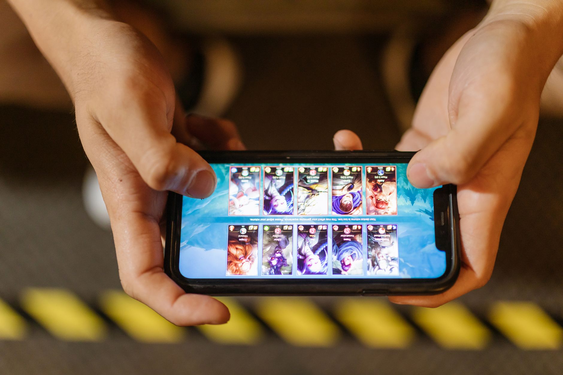 Person holding a smartphone displaying a colorful mobile game interface